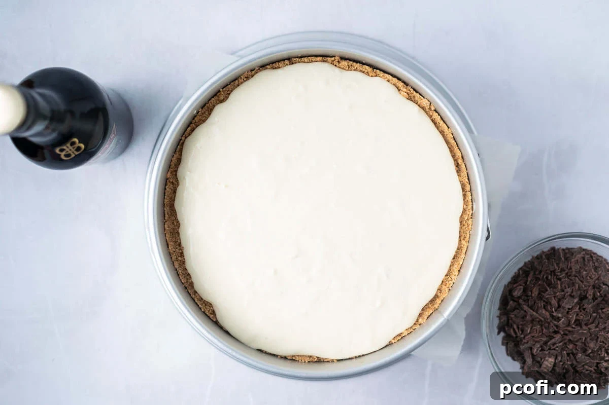 Smooth Baileys cheesecake batter poured into the graham cracker crust in a baking pan.
