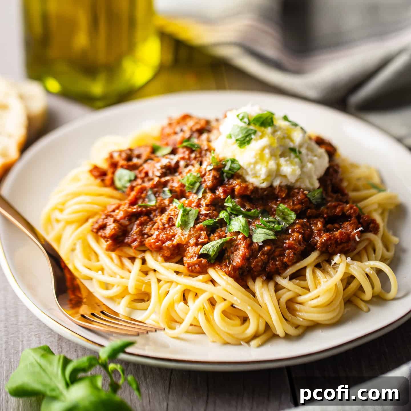 Rich Bolognese sauce generously served over cooked spaghetti, topped with a dollop of fresh ricotta cheese and fresh basil.
