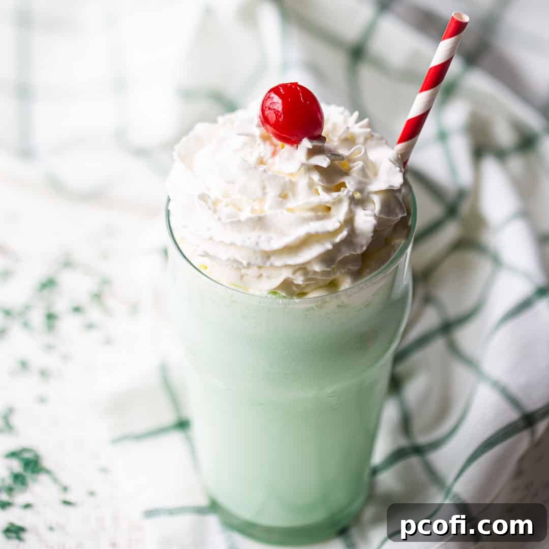 A refreshing Shamrock Shake in a tall glass, topped with whipped cream and a cherry.