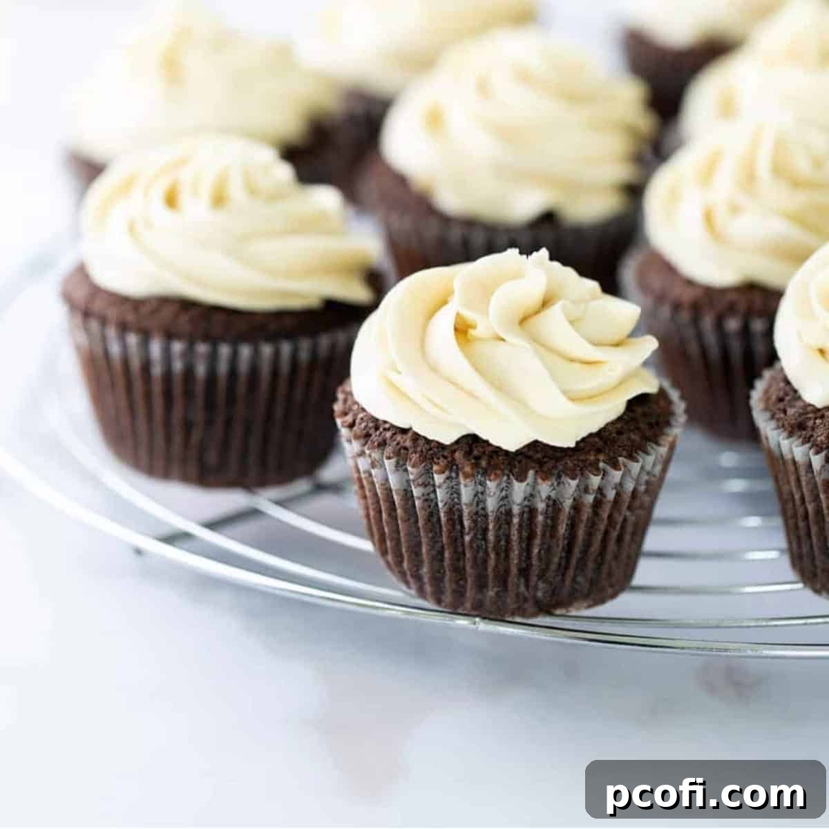 Irish cream cupcakes with a swirl of buttercream frosting on a wire rack.