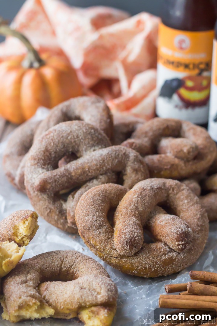 A close-up of a perfectly twisted pumpkin beer soft pretzel, generously dusted with homemade pumpkin spice sugar. Irresistibly sweet and savory, a true taste of fall.