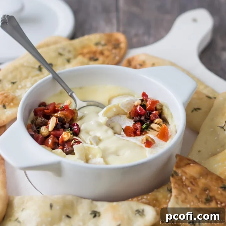Creamy baked cheese appetizer with roasted red pepper relish and herbed flatbreads, perfect for entertaining