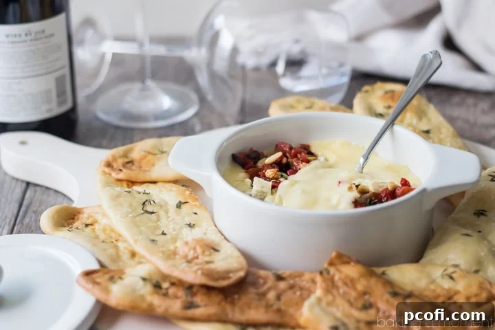 Serving board with baked cheese, roasted red pepper relish, and a side of herbed flatbreads for an elegant appetizer spread