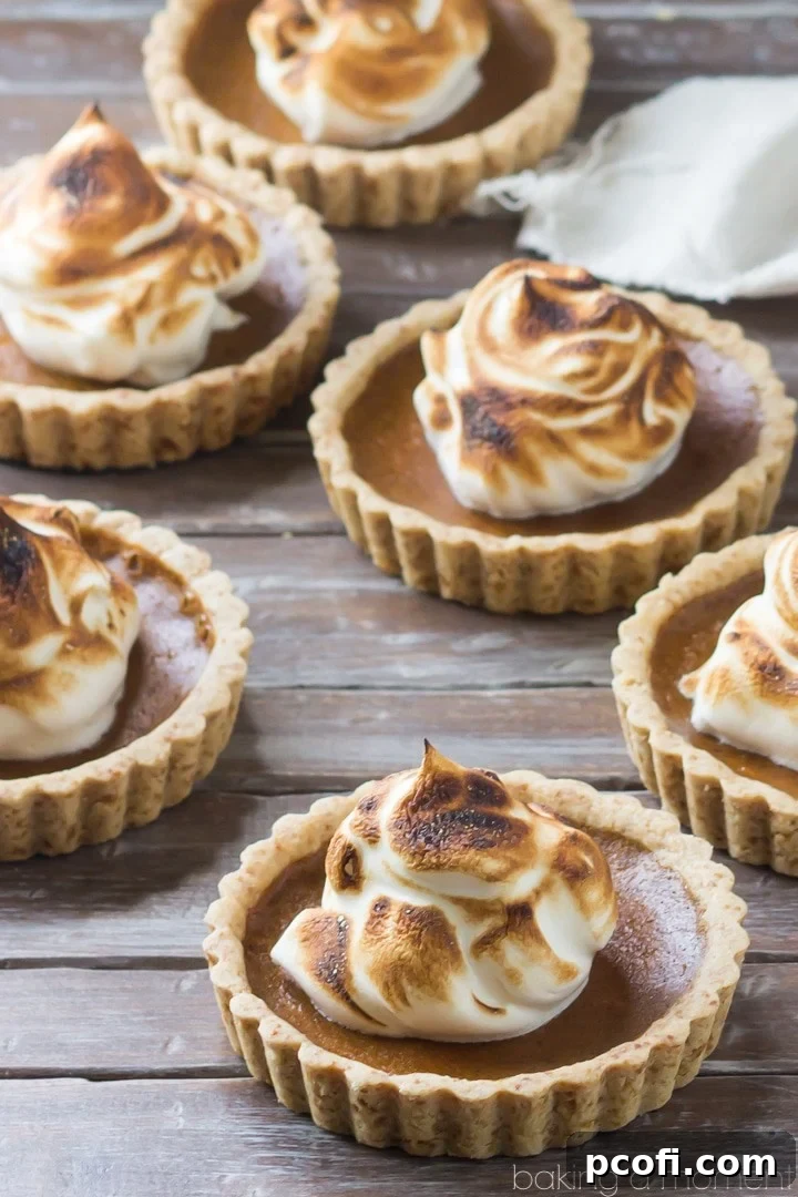 Arrangement of mini pumpkin meringue tarts, showcasing the golden shortbread crust and delicate meringue.