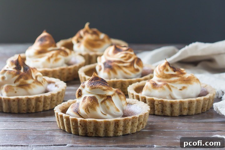 Several mini pumpkin meringue tarts arranged on a serving plate, ready for a Thanksgiving dessert spread.