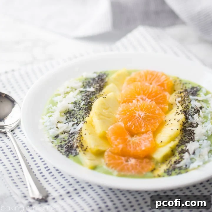 Vibrant tropical green smoothie bowl topped with fresh fruit slices, coconut flakes, and chia seeds.