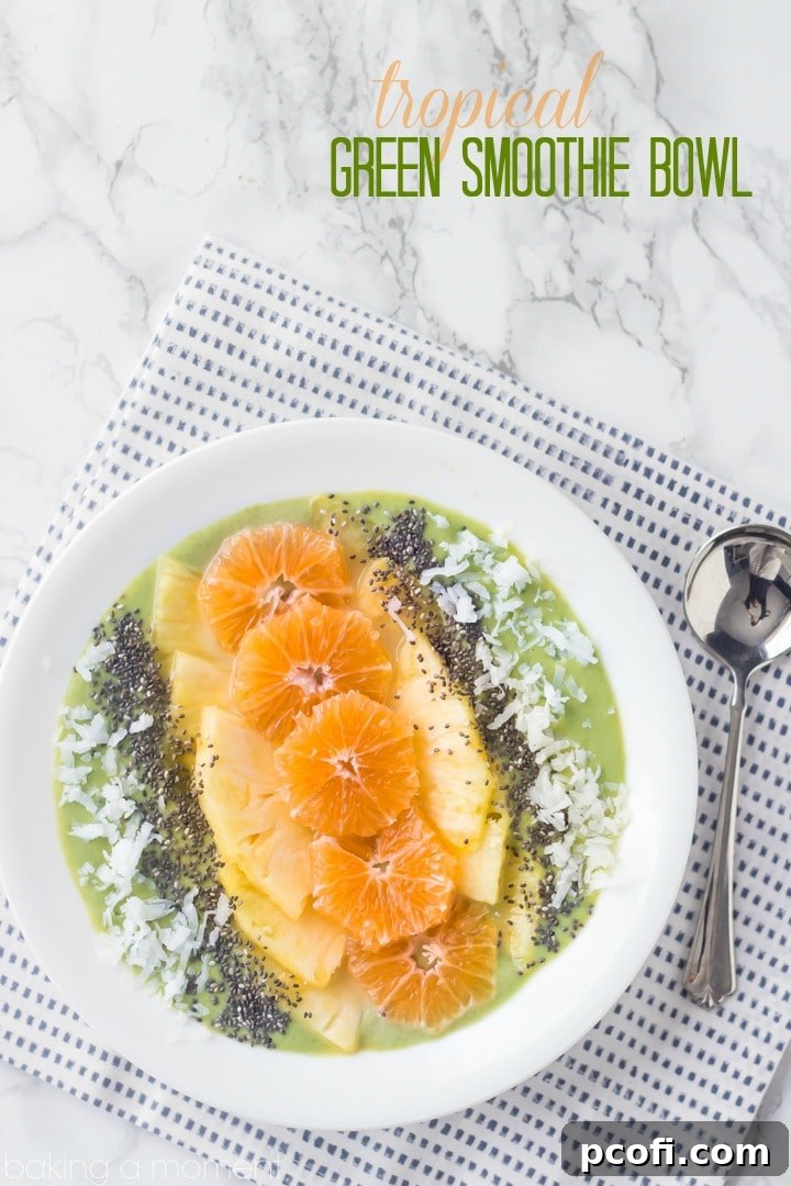 Close-up of a refreshing green smoothie bowl with mango, pineapple, and citrus slices.