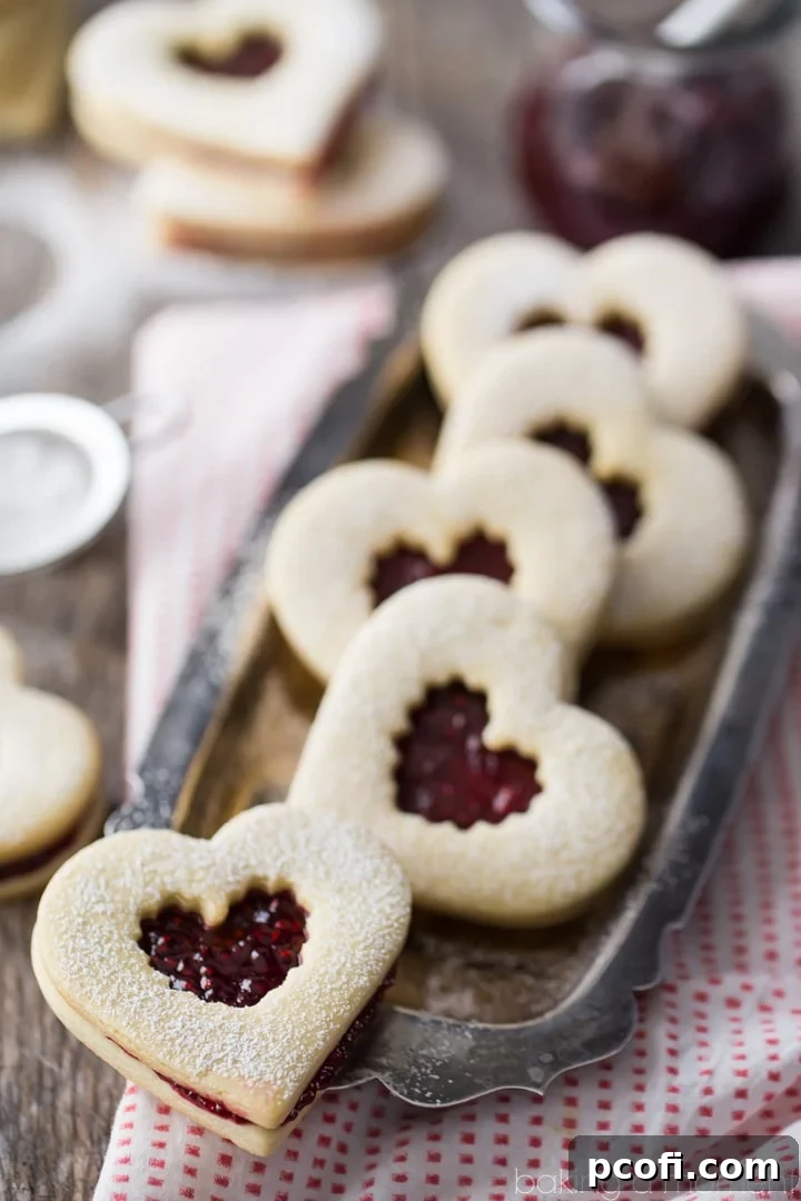 Stack of Raspberry Linzer Cookies showcasing the elegant heart shape and jam filling.