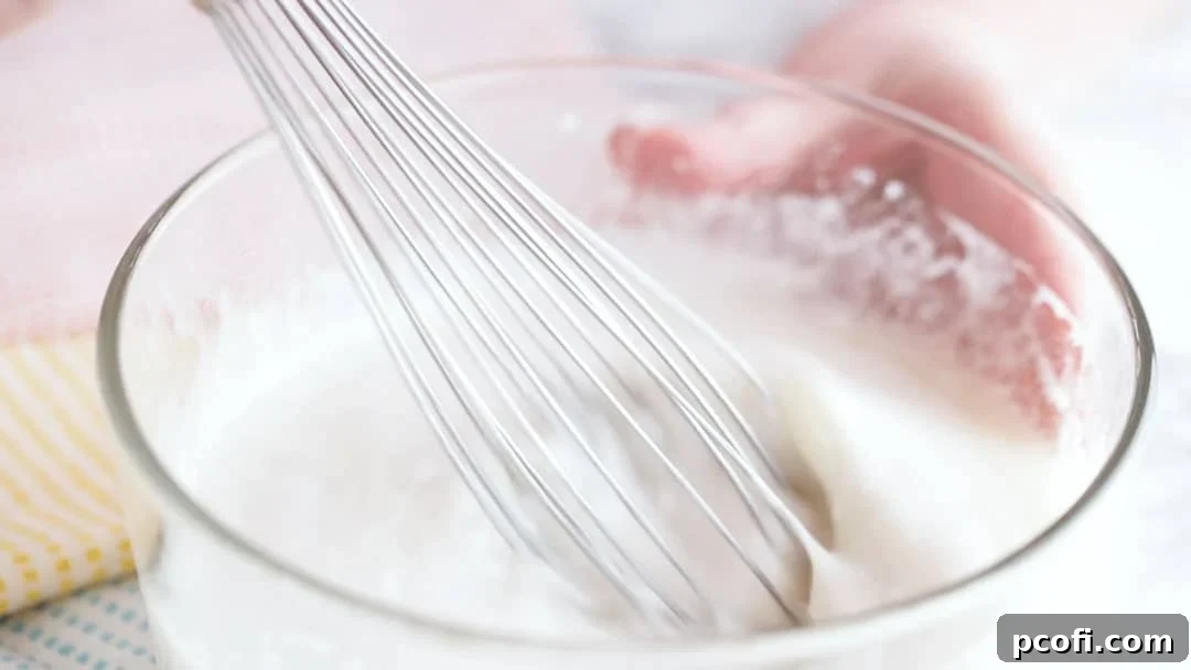 Whisking wet ingredients together for a homemade coconut cake recipe, ensuring thorough mixing before combining with dry ingredients.