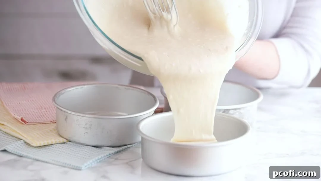 Pouring cake batter into prepared pans, ready to create a perfectly layered coconut cake masterpiece.