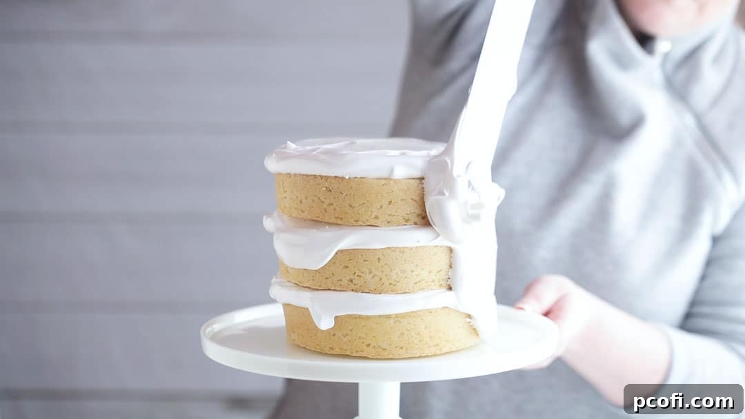 Icing a coconut layer cake with marshmallow frosting, creating a smooth, elegant base for the coconut topping.
