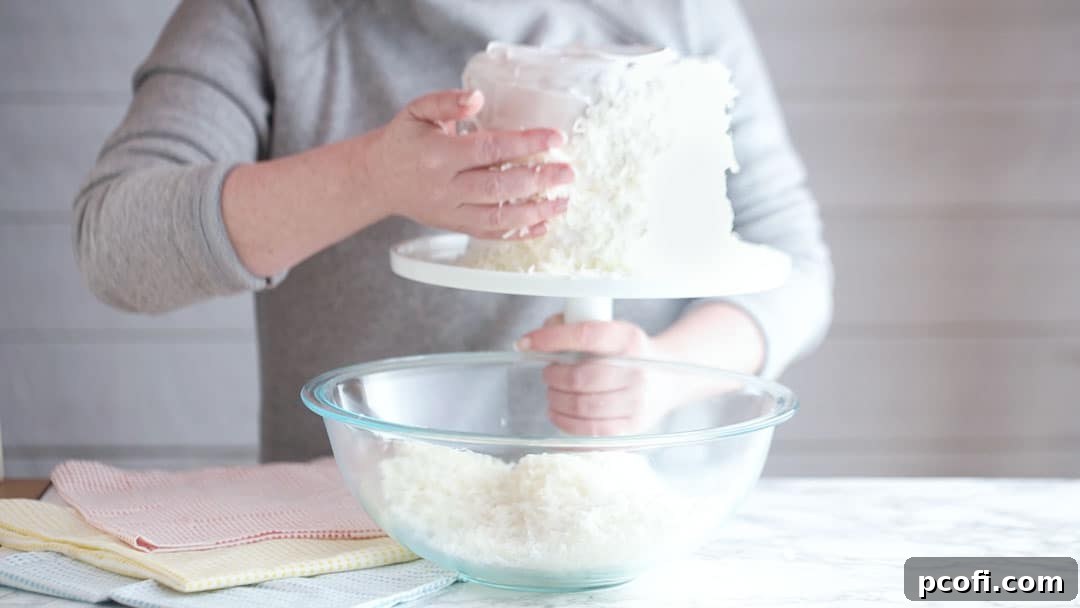 Coating a frosted cake in dessicated coconut, ensuring full coverage for a classic and beautiful finish.