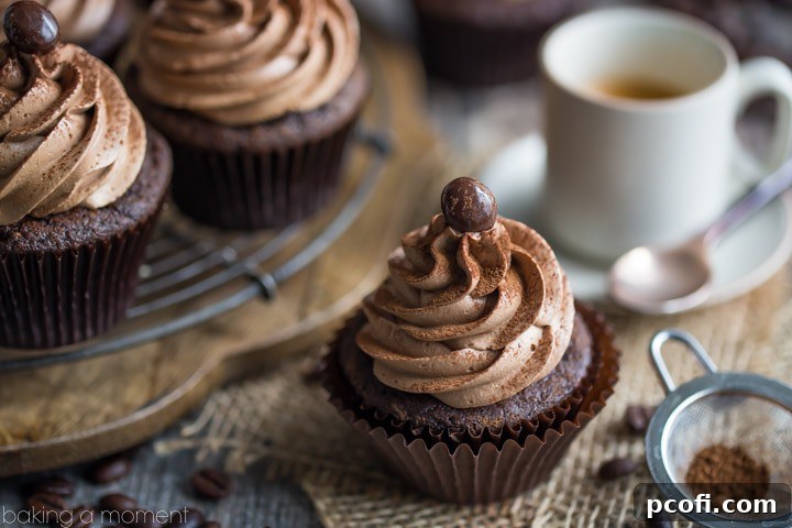 A close-up of a single mocha cupcake, elegantly garnished with a chocolate-covered espresso bean.