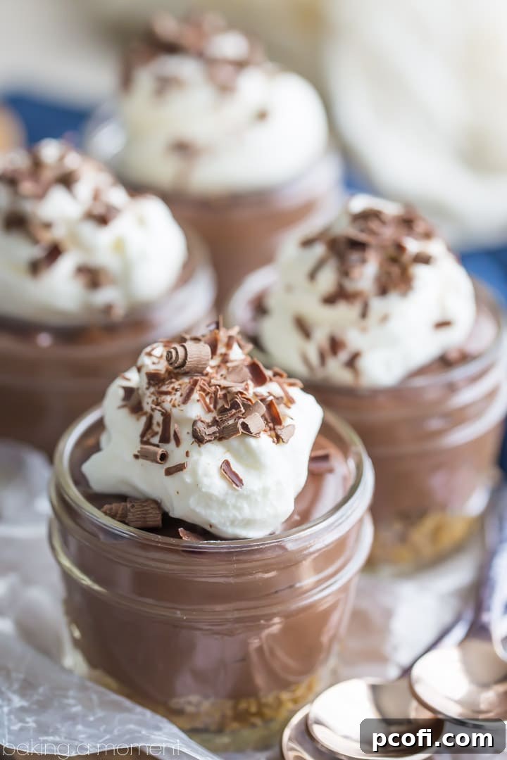 Close-up of homemade chocolate pudding in a jar with a graham cracker crust and whipped cream.