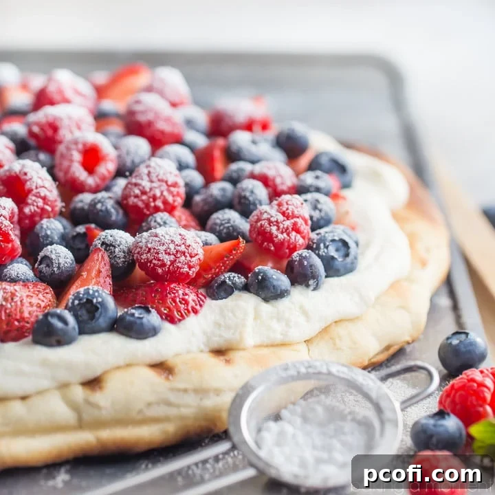 Beautifully presented grilled berry pizza with whipped ricotta, fresh berries, and a sprinkle of powdered sugar, ready to be served as a summer snack or dessert.
