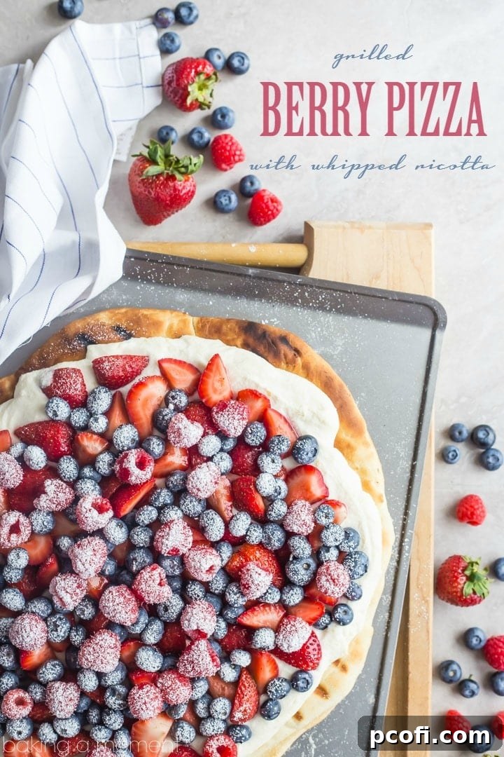 Close-up overhead shot of a grilled whole wheat pizza crust generously topped with fluffy whipped ricotta, vibrant red strawberries, and blue blueberries.