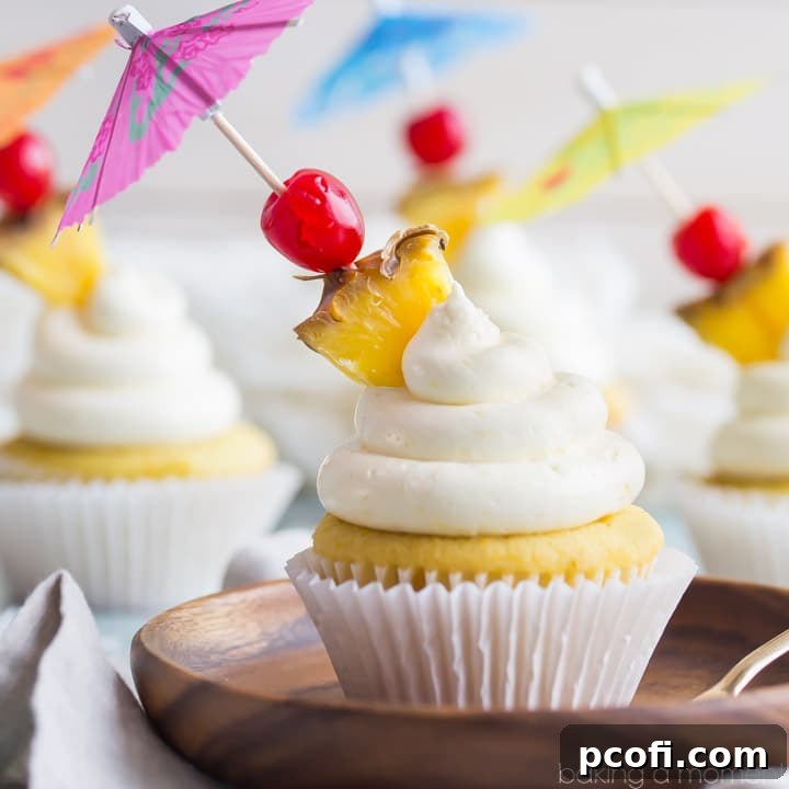 Pina Colada Cupcakes: A delicious dessert inspired by the classic tropical cocktail, featuring vibrant pineapple, creamy coconut, and a hint of rum, garnished with a cherry and pineapple slice for a festive treat.
