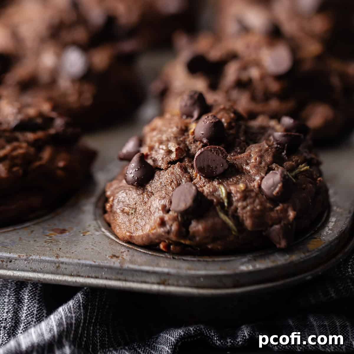 Close-up of a freshly baked chocolate zucchini muffin in a vintage muffin tin.