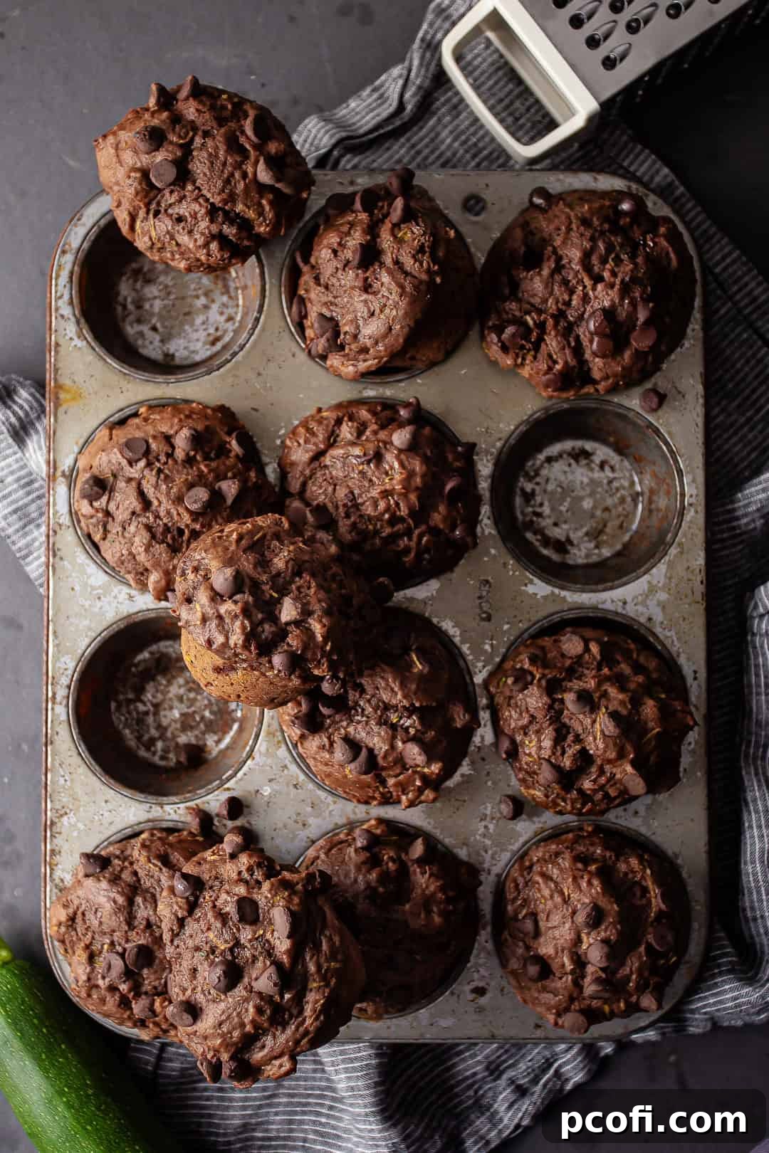 Overhead image of a tin of freshly baked chocolate zucchini muffins on a dark background.