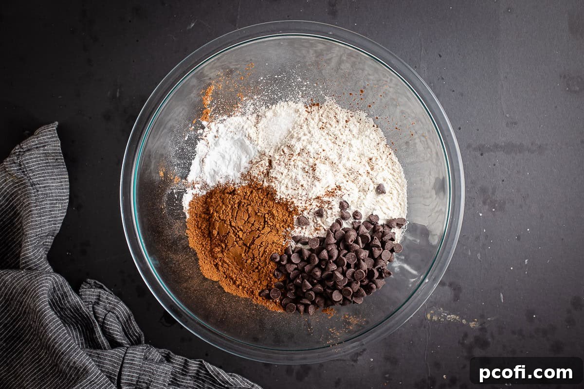 Dry ingredients for making chocolate zucchini muffins in a large glass bowl.