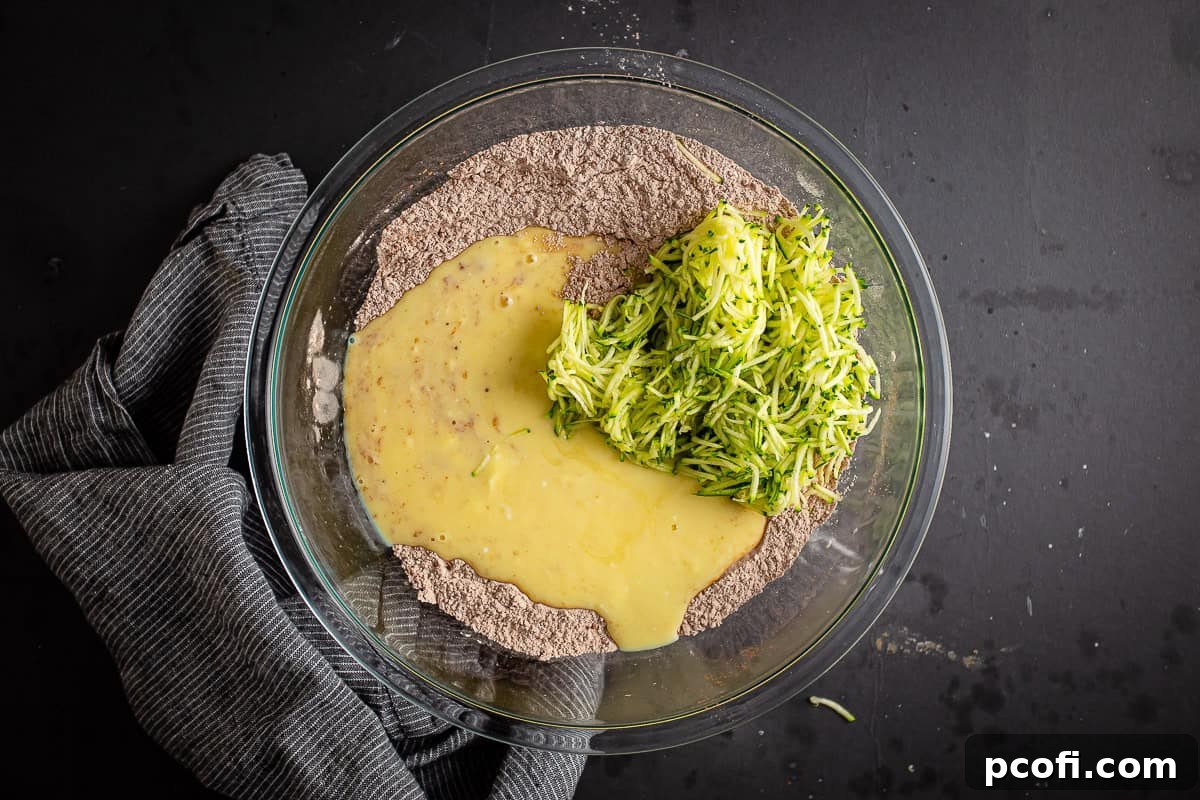Mixing dry and liquid ingredients together with shredded zucchini.