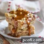 A delicious Caramel Apple Oatmeal Carmelita Bar, featuring a golden brown oatmeal crust, spiced apple filling, and gooey caramel drizzle.