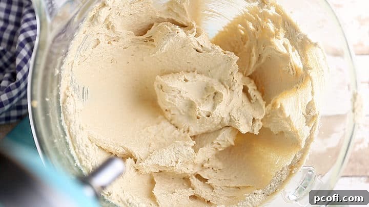 Creamed butter, brown sugar, and white granulated sugar in a mixing bowl, showing a pale and fluffy texture.