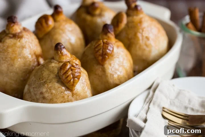 A close-up of a pear dumpling, showcasing the flaky pastry, tender fruit, and glossy cinnamon sauce – a truly indulgent fall treat.