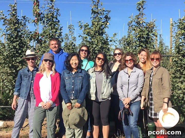 A group photo of food bloggers and a Stemilt farmer during the 2016 Stemilt Blogger Tour in Washington's pear orchard, surrounded by beautiful trees.