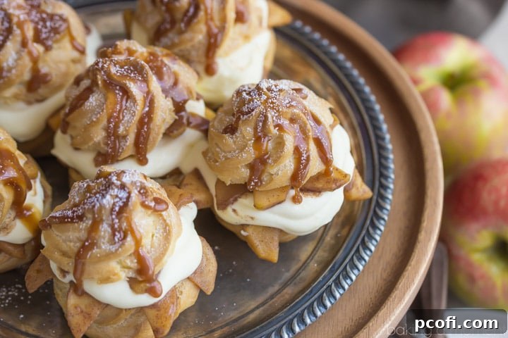 A close-up of a halved Caramel Apple Cream Puff, showing the layers of choux pastry, fluffy cream, and caramelized apple slices within, with a sweet caramel drizzle.