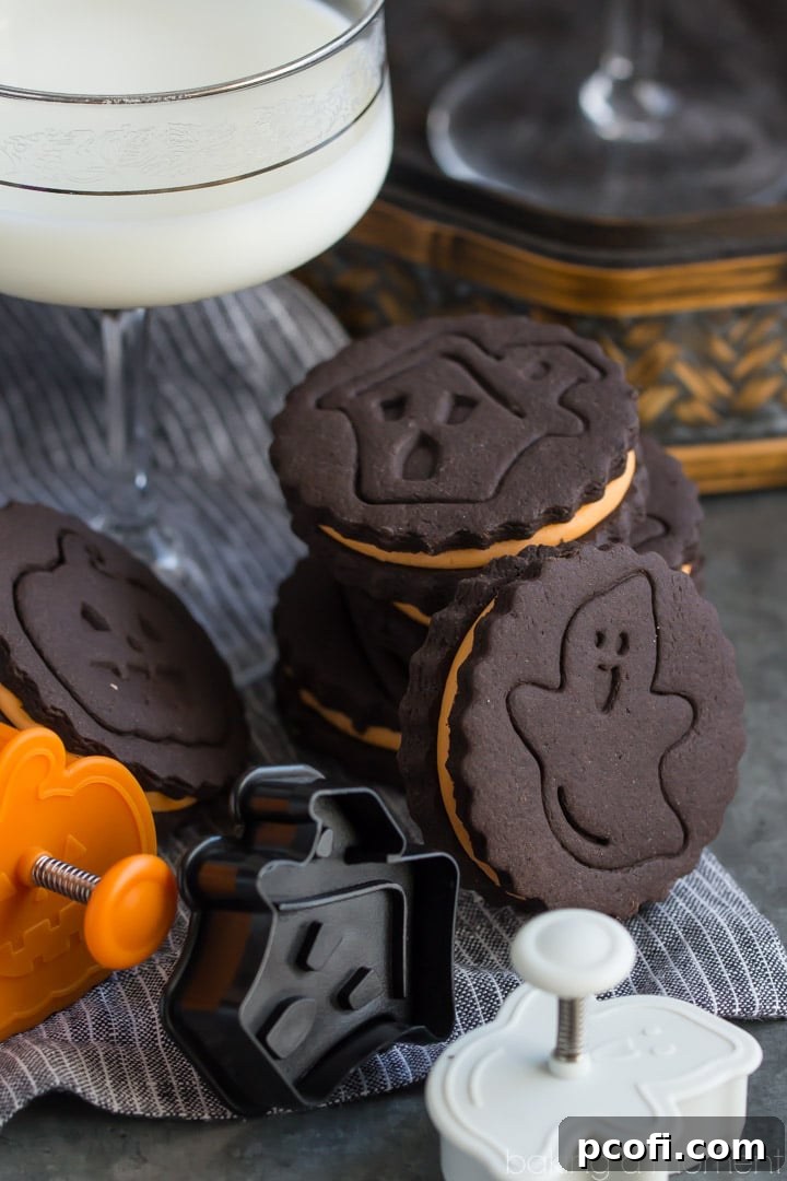 A baker stamping a freshly cut chocolate cookie dough with a Halloween design on parchment paper