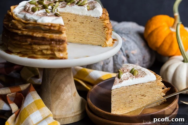 A close-up of a slice of Pumpkin Crepe Cake, garnished with salted caramel, whipped cream, and toasted pepitas, showcasing its irresistible layers.