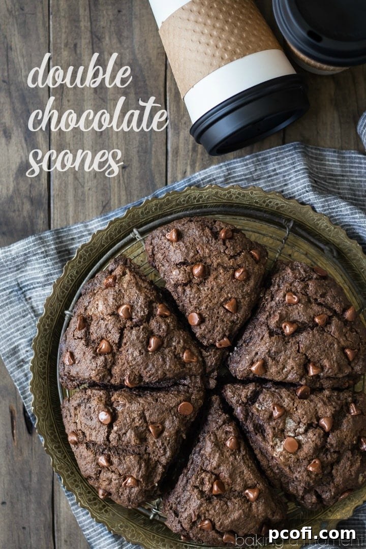 A close-up of a double chocolate scone, showcasing its flaky texture and abundant chocolate chips, ready to be enjoyed with coffee.