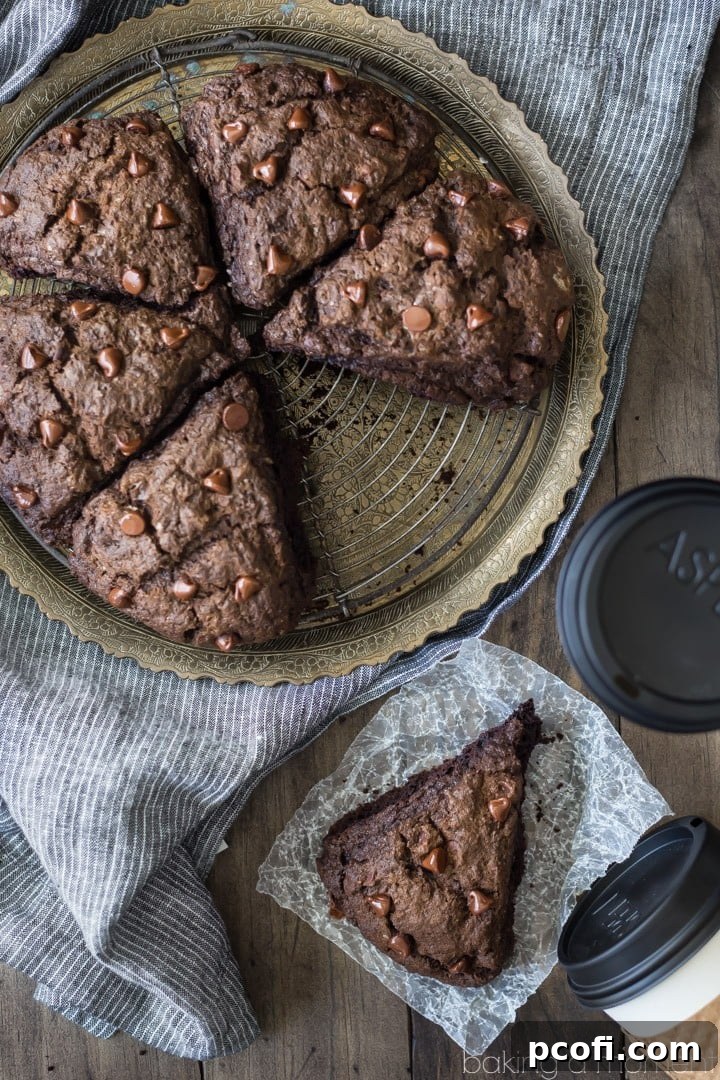 A stack of perfectly baked double chocolate scones, dusted with a light touch of powdered sugar, presented on a rustic board.