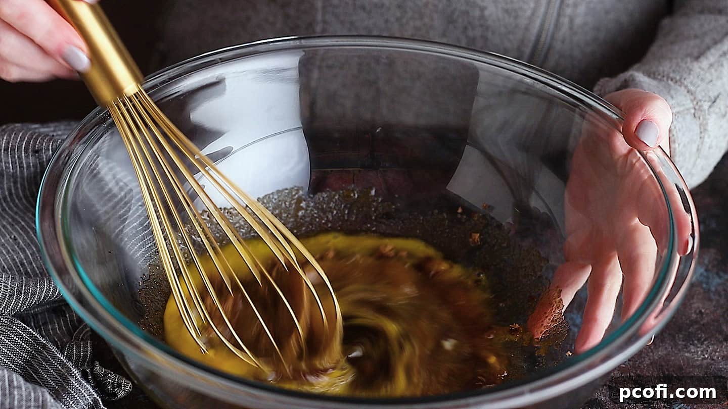 Whisking eggs and dark brown sugar together until light and fluffy, forming the essential base for the chocolate pecan pie filling.
