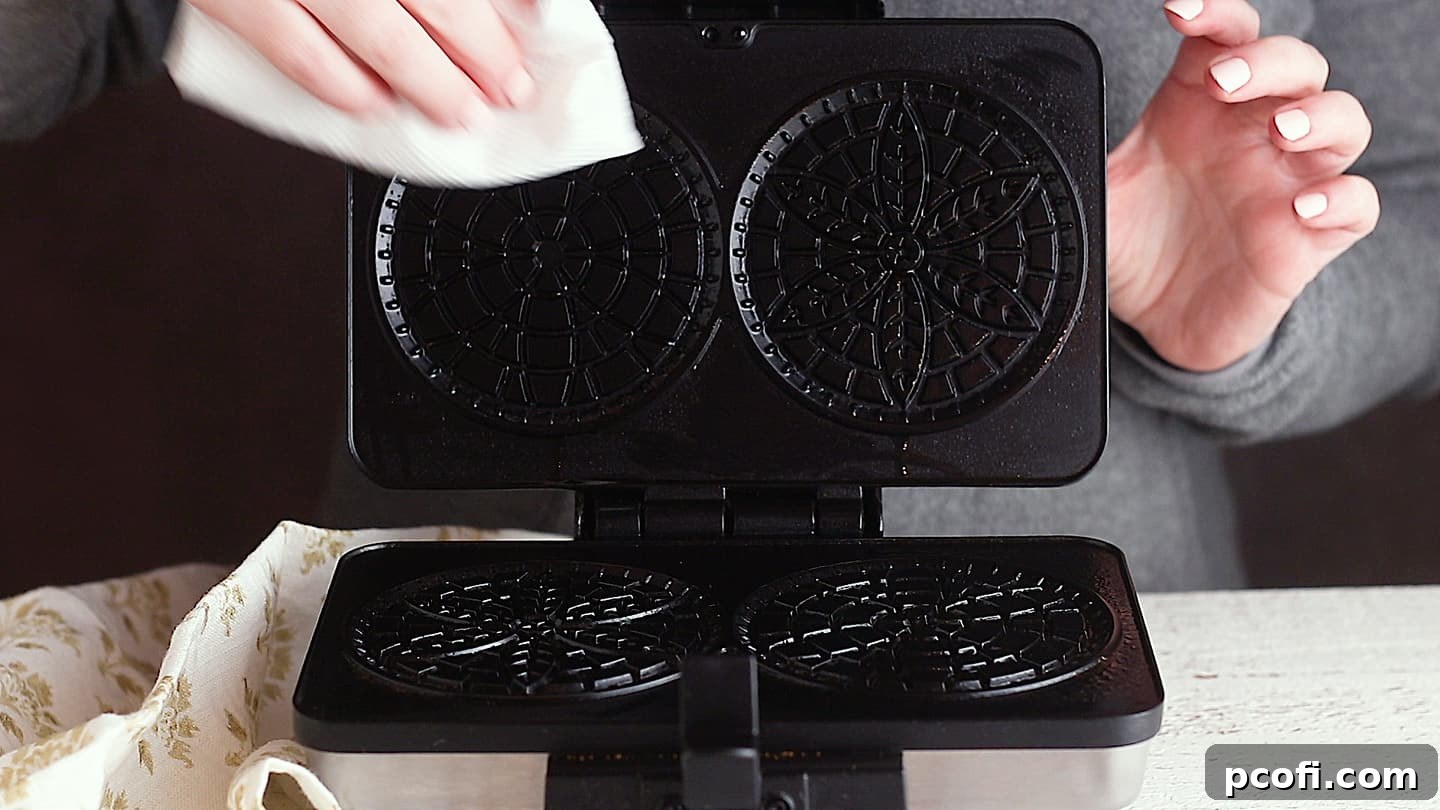 Lightly greasing a pizzelle maker.