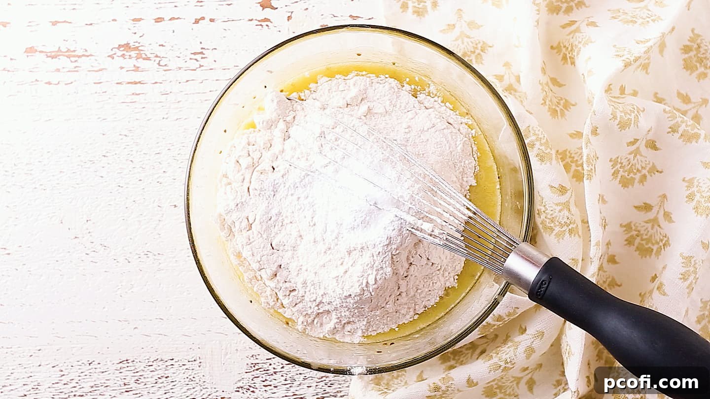 Adding flour, baking powder, and salt to pizzelle batter.