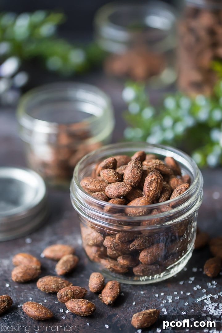 Raw almonds being tossed with gingerbread spices and molasses in a bowl before baking.