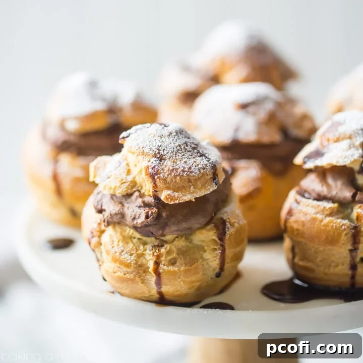Golden-brown Mocha Cream Puffs filled with fluffy chocolate-coffee diplomat cream, dusted with powdered sugar and drizzled with chocolate syrup, ready for a special treat.