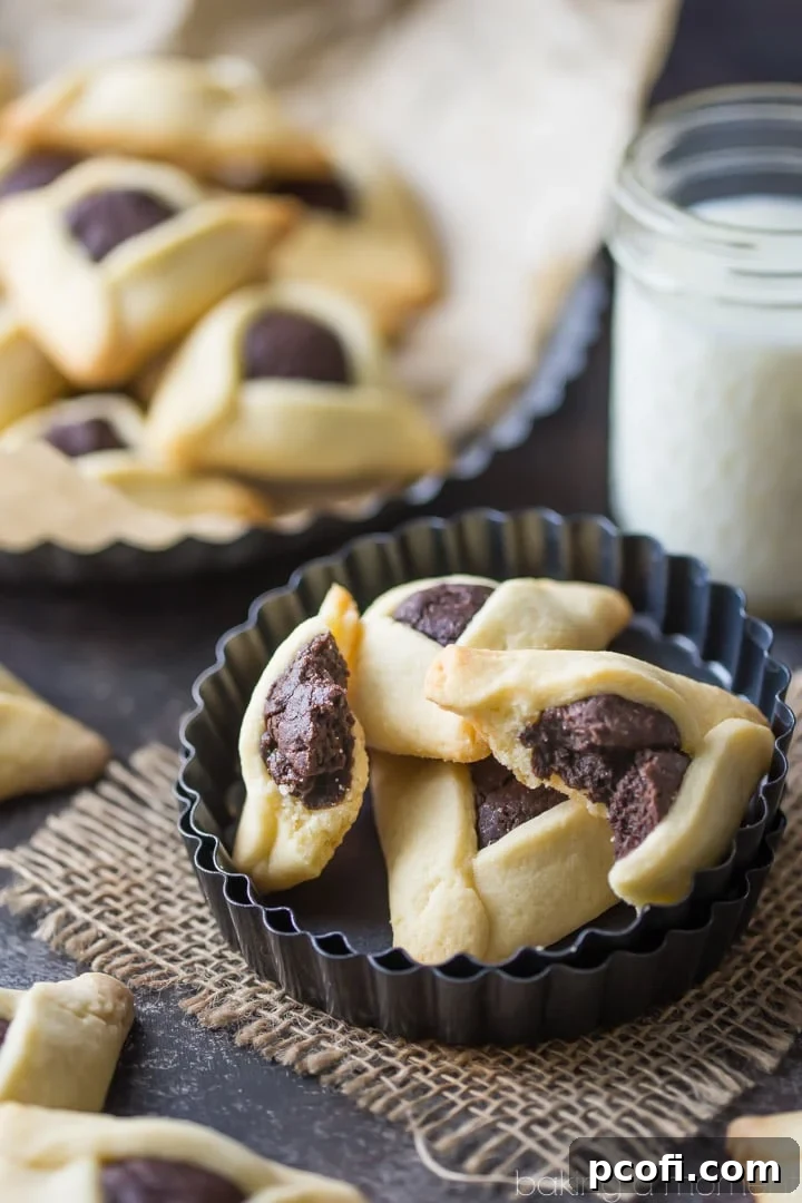 Fudge Brownie Hamantaschen - Stacked hamantaschen cookies with a close-up on the gooey brownie center, emphasizing the rich chocolate texture against the crisp cookie edge.