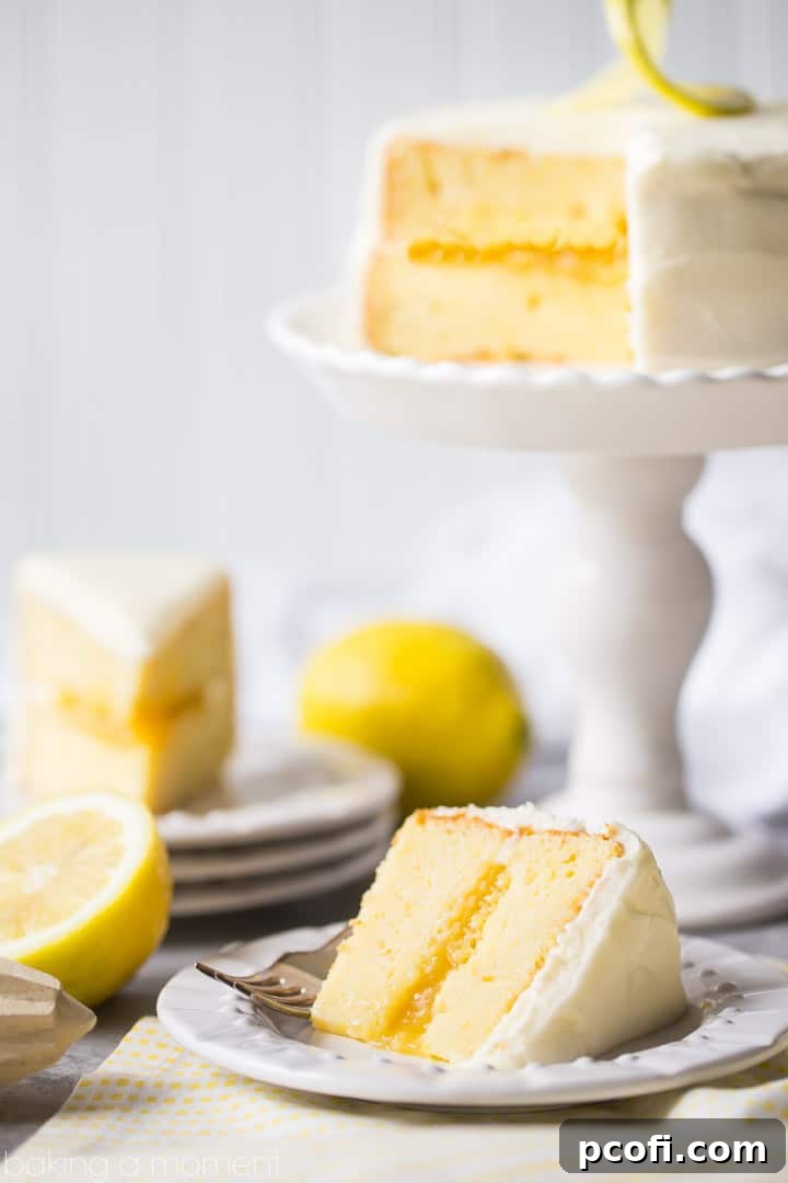 Close-up of a slice of mini lemon cake showing the lemon curd filling and cream cheese frosting.