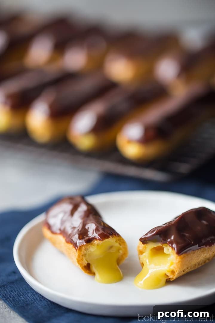 Close-up of three finished eclairs, showcasing the glossy chocolate glaze and hinting at the creamy vanilla filling.