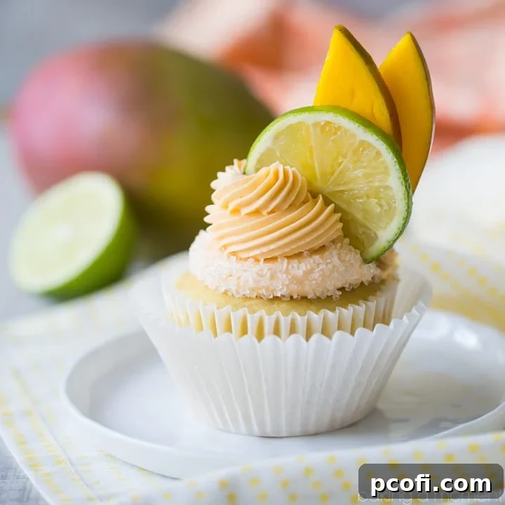 Mango Margarita Cupcakes: a bright yellow cupcake with a salted sugar rim and a swirl of creamy mango margarita buttercream, garnished with fresh lime and mango slices.