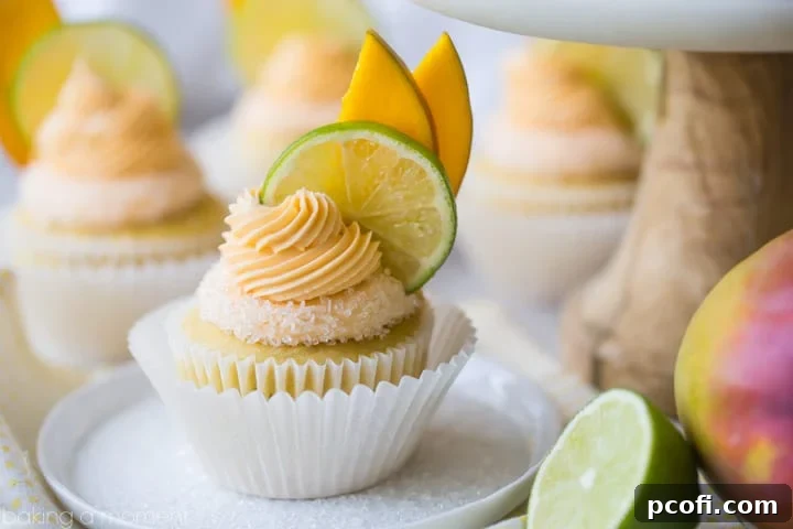 Mango Margarita Cupcakes: A closeup of a vibrant yellow cupcake, adorned with a sparkling salted rim and a lavish swirl of mango margarita buttercream, beautifully garnished with delicate lime and mango slices.