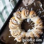 A delicious Swedish Tea Ring on a cooling rack, drizzled with glaze.