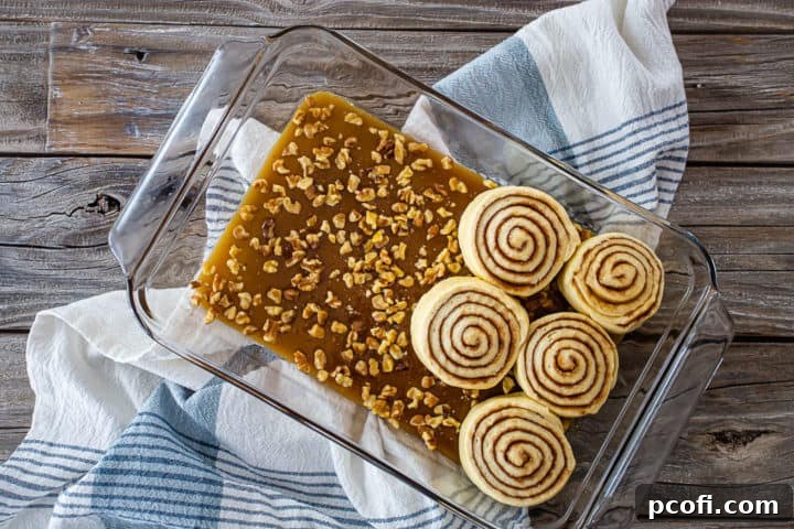 Placing unbaked sticky buns in a glass baking dish, on top of the sticky bun topping.