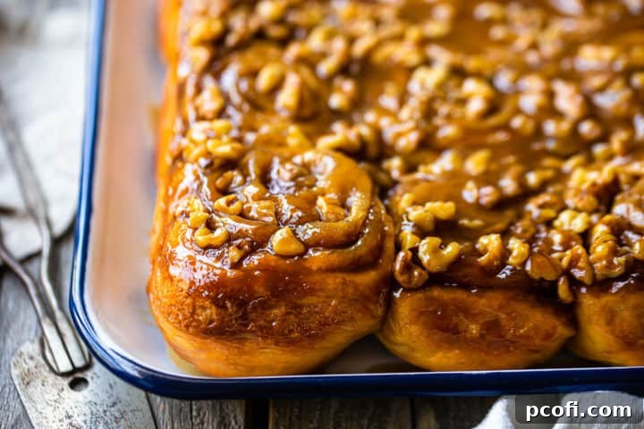 Close-up image of homemade sticky buns on a white tray with a vintage cake server.