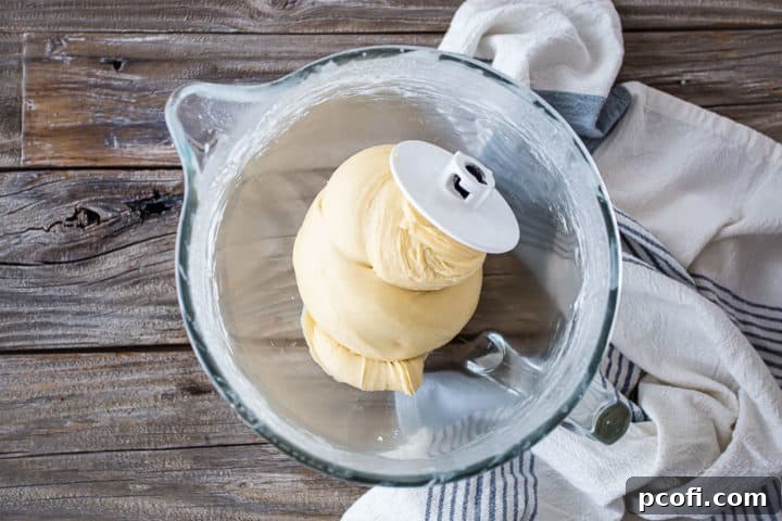 Kneading sticky bun dough in a stand mixer with a dough hook attachment.