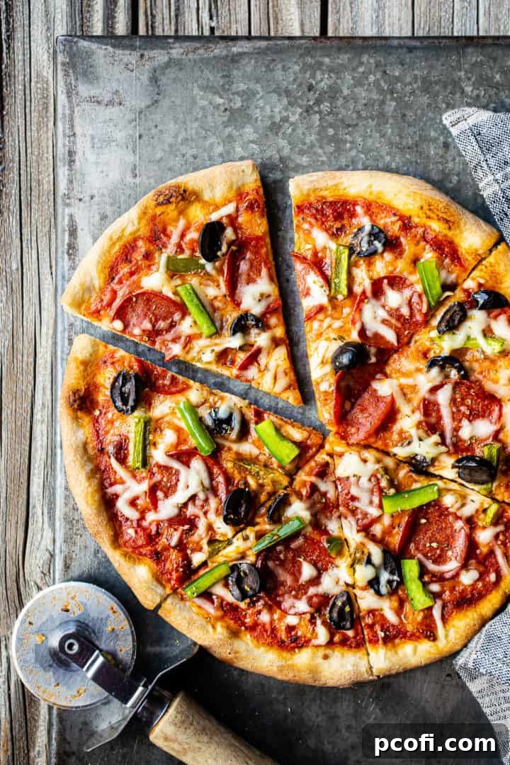An easy pizza dough recipe, transformed into a delicious baked pizza with vibrant toppings, showcased on a metal tray with a pizza cutter.