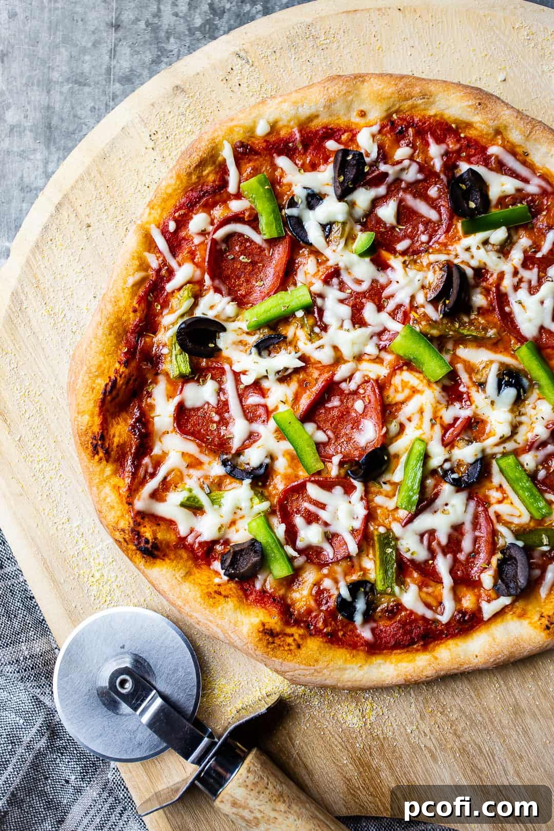 Delicious homemade pizza, topped with fresh ingredients and served on a pizza peel with a cutting wheel.